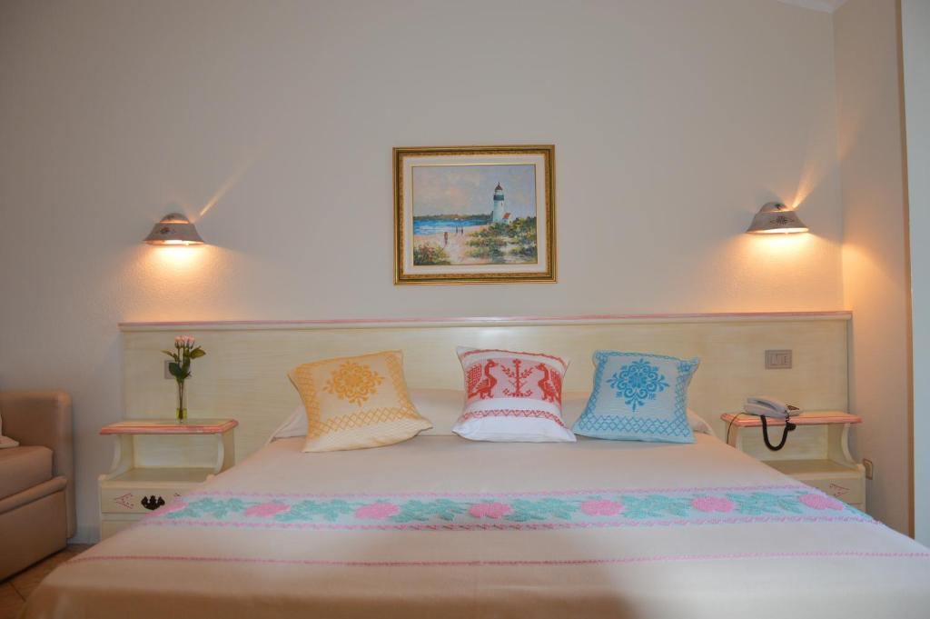 a bedroom with a large bed with colorful pillows at Hotel La Palma in San Teodoro