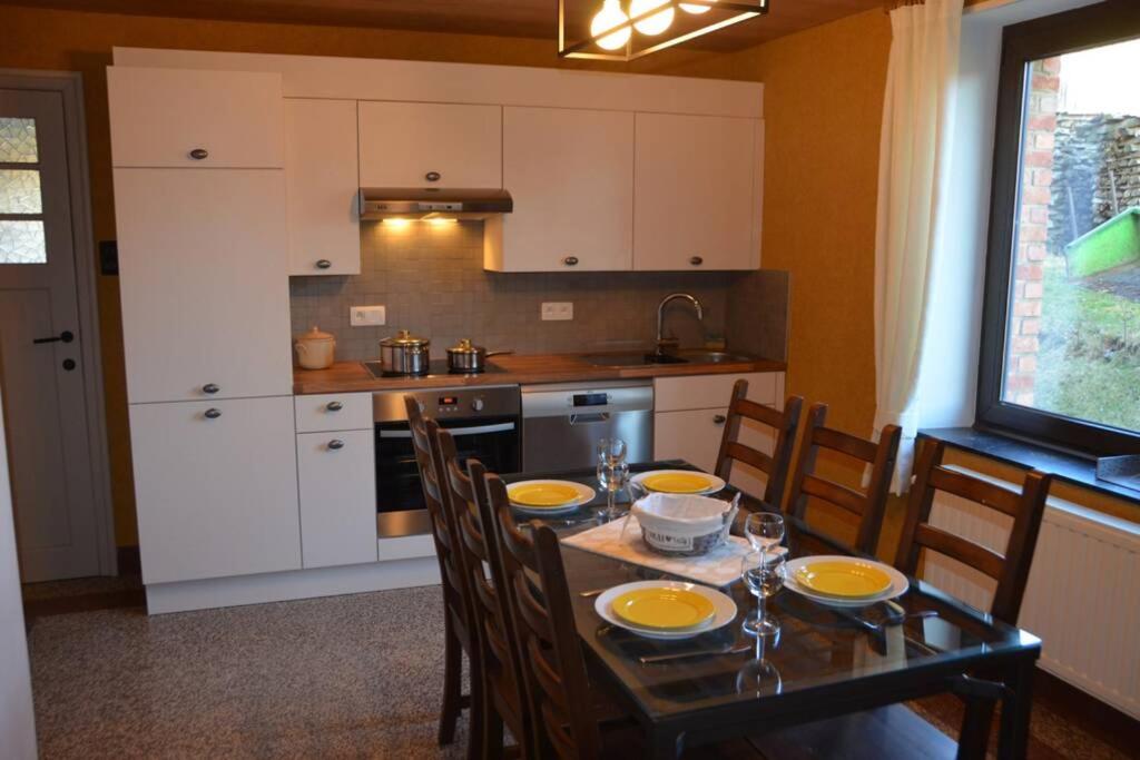 una cocina con mesa con sillas y un asterisco de mesa en Chez Pèpère, gîte charmant et tranquille, en Trois-Ponts