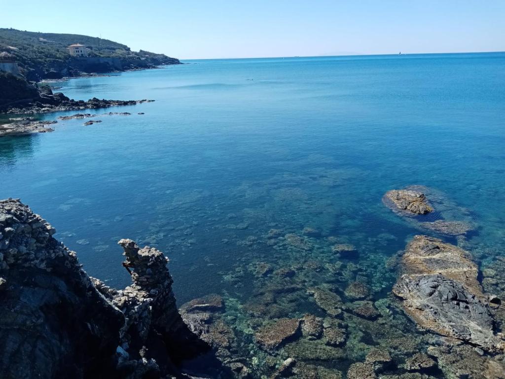 a view of a body of water with rocks at Caletta Beach in Castiglioncello