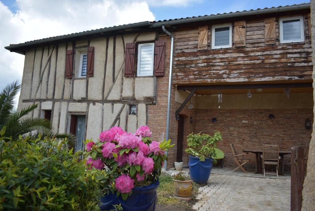 une maison avec des fleurs roses devant elle dans l'établissement Maison de charme dans le Gers, à Noilhan