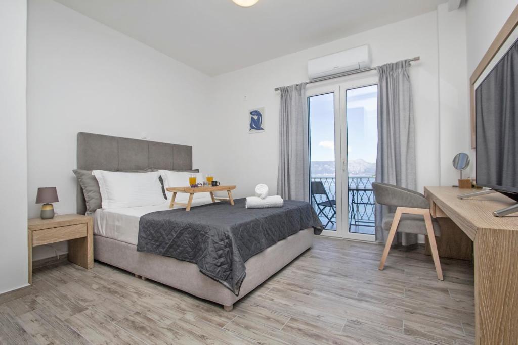 Dormitorio con cama, escritorio y TV en Vidos Seaview Suite en Corfú