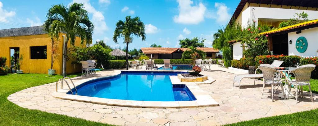 - une piscine dans une cour avec des chaises et une maison dans l'établissement Pousada Aconchego, à Pitimbu