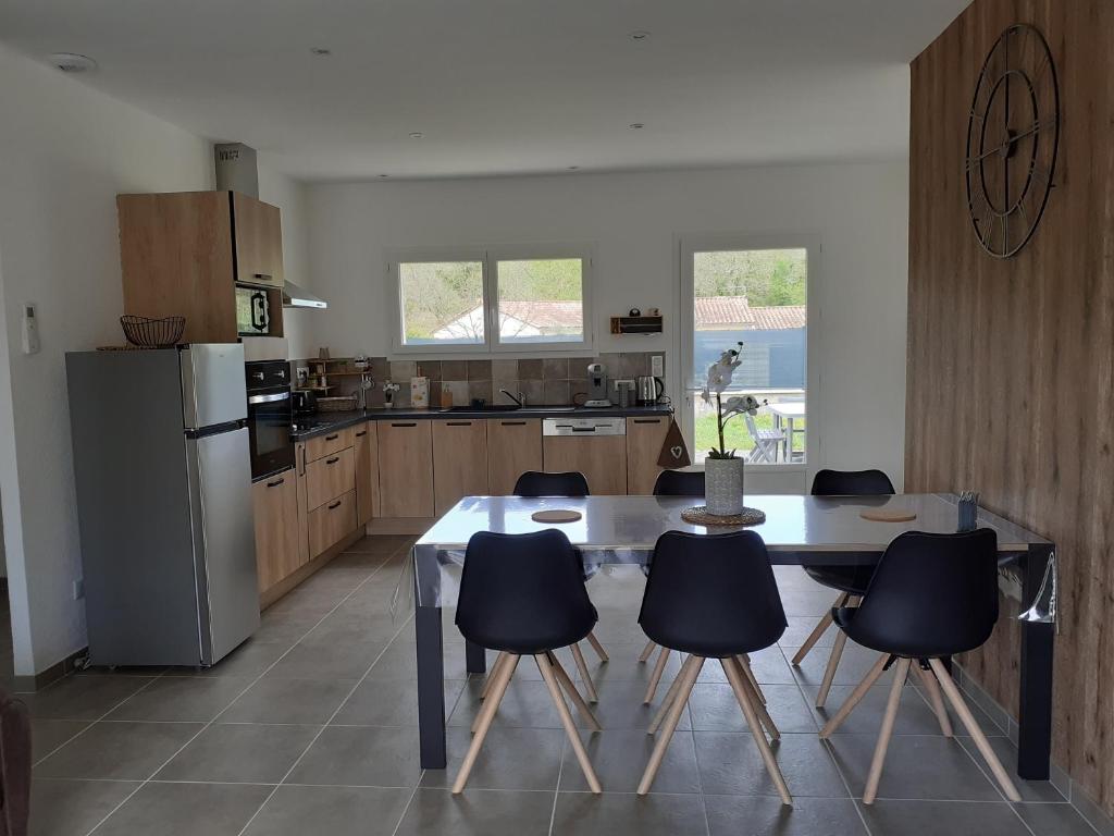 a kitchen with a table and chairs and a refrigerator at Les LOCS Du GRAZEL in Ruoms