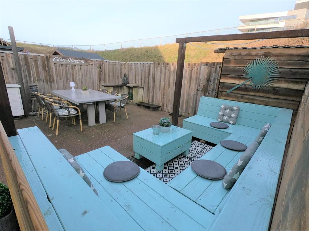 une terrasse avec un banc bleu et une table dans l'établissement Casa Nuestra, à Egmond aan Zee