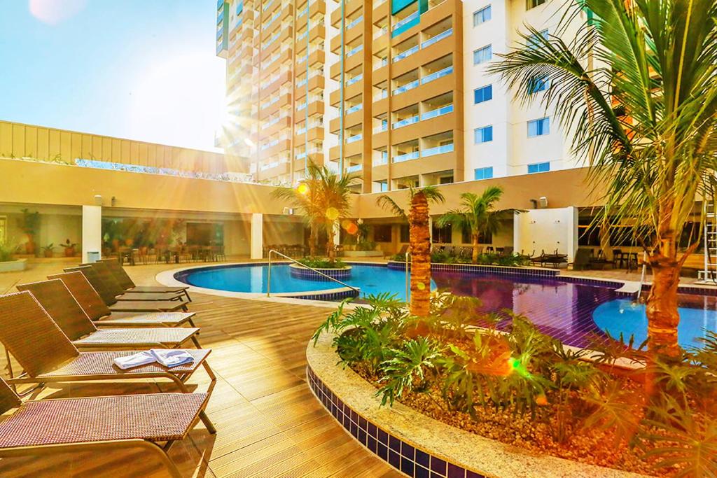 un hotel con una piscina con tumbonas y palmeras en OLIMPIA PARK RESORTs "MELHOR PREÇO ", en Olímpia
