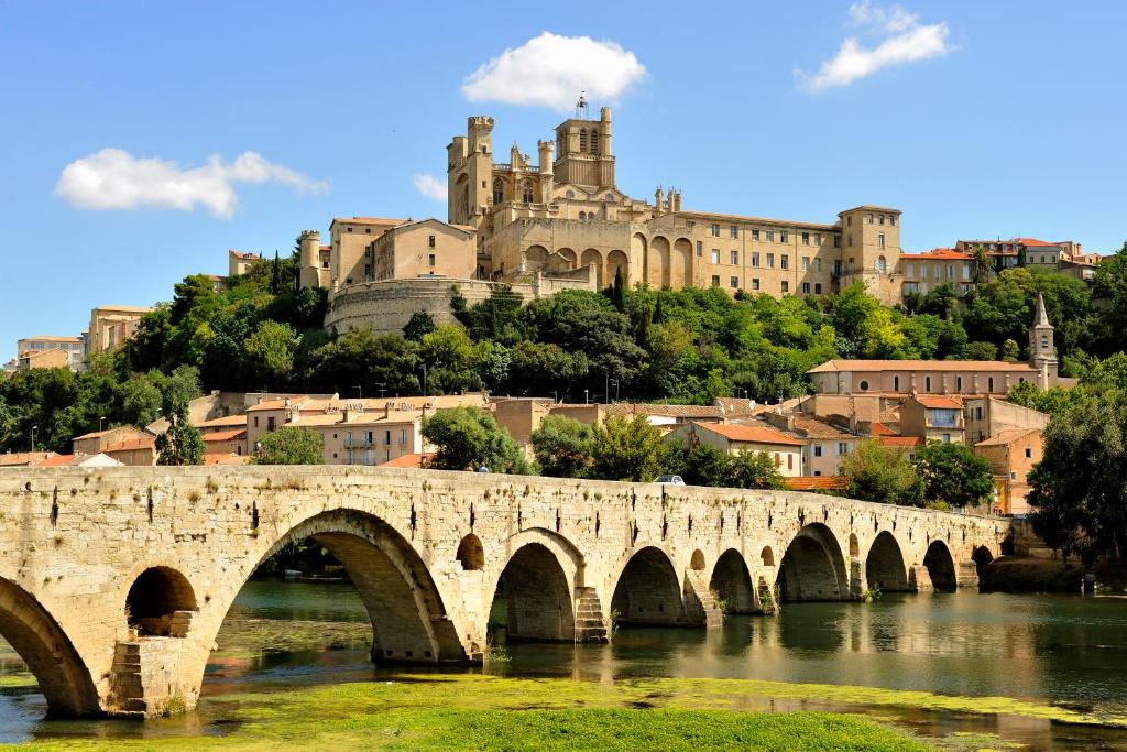 a bridge over a river with a castle in the background at "Le Patio"-Meublé de Tourisme 3 étoiles -Résidence "Les Logis de Béziers"-Garage optionnel-Cœur de ville-Plages à 16km ! in Béziers