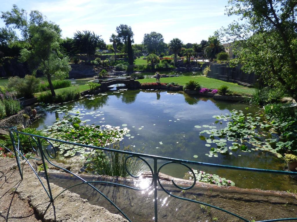 a pond in a park with a bridge and flowers at "Le Patio"-Meublé de Tourisme 3 étoiles -Résidence "Les Logis de Béziers"-Garage optionnel-Cœur de ville-Plages à 16km ! in Béziers
