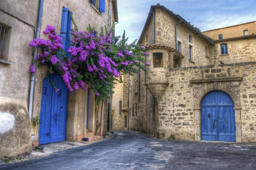 an alley with blue doors and purple flowers at "Le Patio"-Meublé de Tourisme 3 étoiles -Résidence "Les Logis de Béziers"-Garage optionnel-Cœur de ville-Plages à 16km ! in Béziers