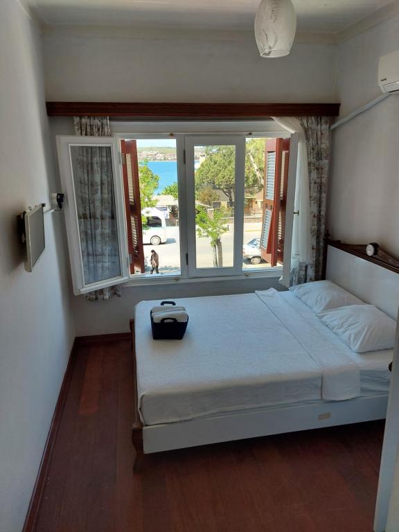 a bedroom with a bed with a large window at Celil Pansiyon in Ayvalık