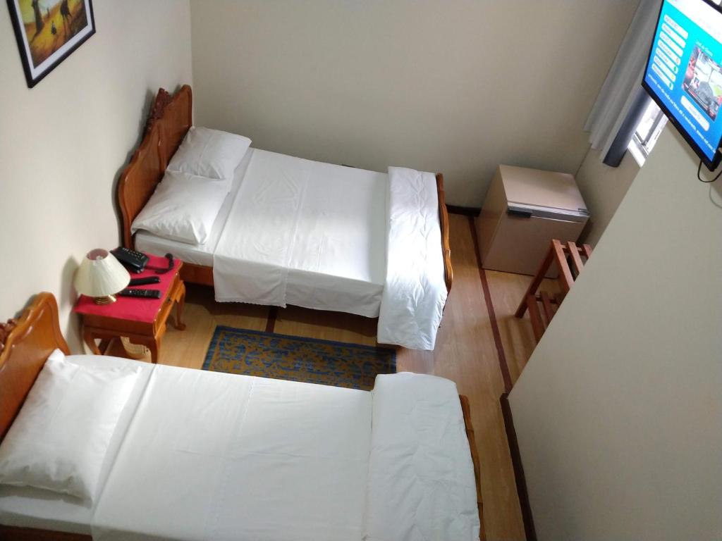 a small room with two beds and a television at Hotel Cervantes in Curitiba