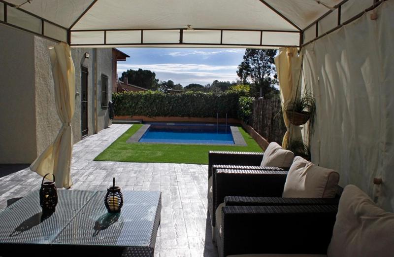 a patio with a couch and a table and a pool at Villadora in Santa Coloma de Farners
