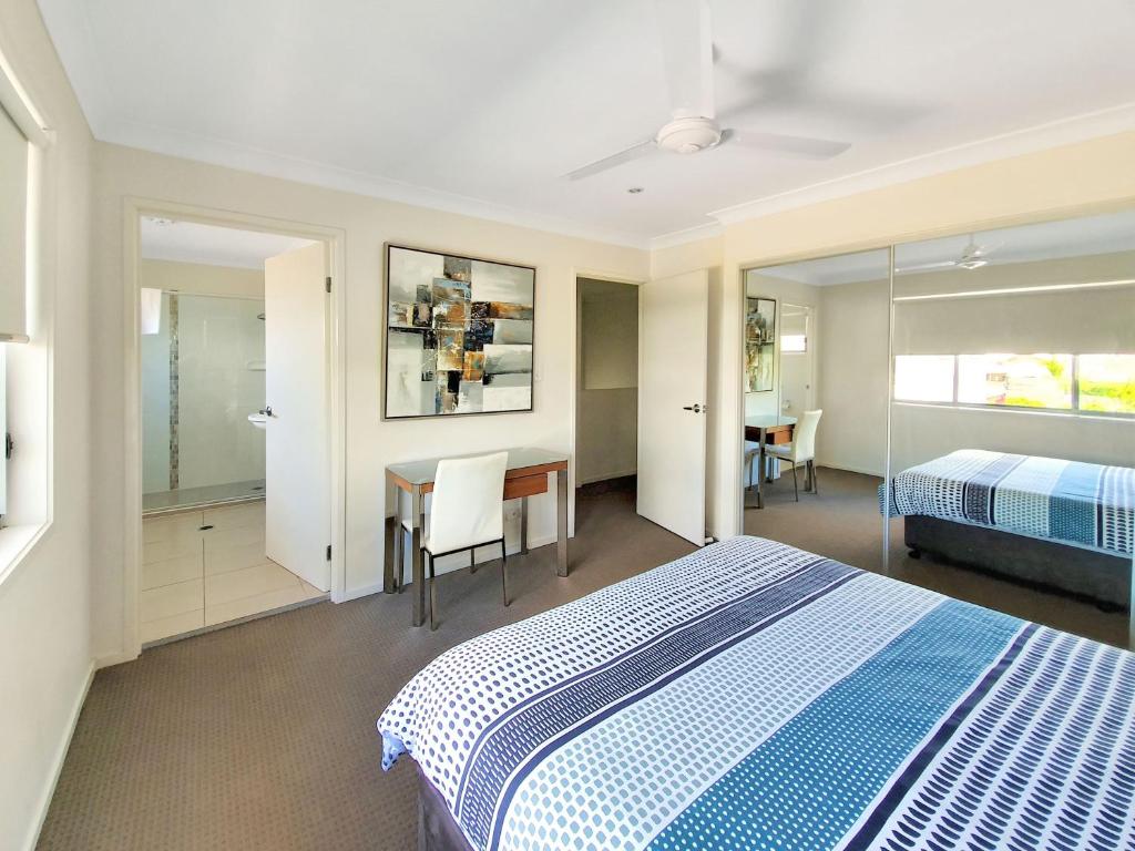 een slaapkamer met een bed, een bureau en een tafel bij Lillypilly Resort Apartments in Rockhampton