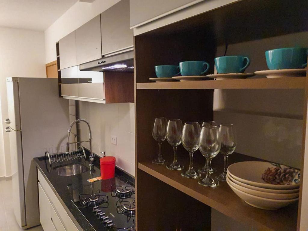 a kitchen with wine glasses on a counter at Apartamento novo , poucos metros da praia com WI FI in Ubatuba