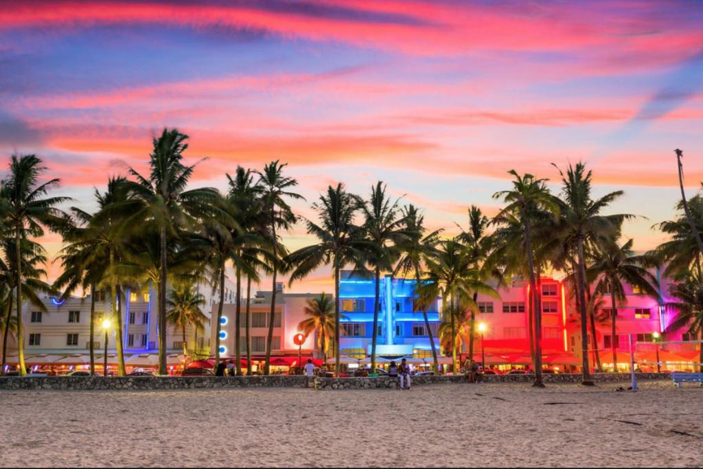 - une plage avec des palmiers et des bâtiments au coucher du soleil dans l'établissement SNUG MINIMALIST FULL BED NEAR DOLPHIN MALL/FIU, à Miami