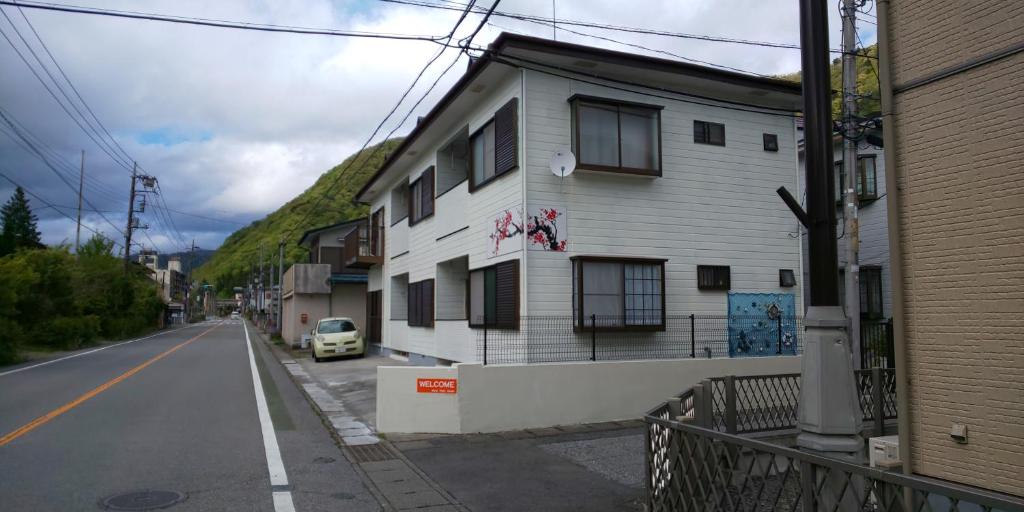 un bâtiment blanc sur le côté d'une rue dans l'établissement Akira Peak House Kinugawa, à Kinugawaonsen Ohara