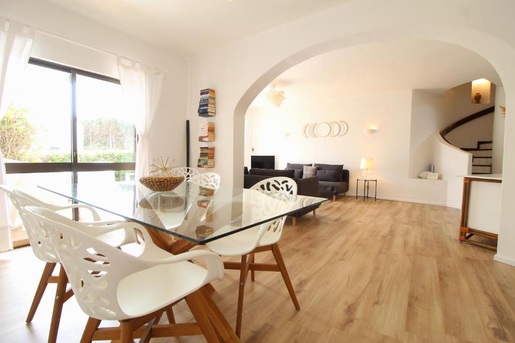 comedor con mesa de cristal y sillas blancas en Rustic Beach House at the Cliff T3 | C218, en Porches