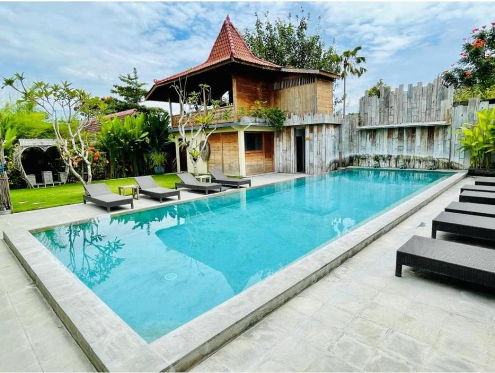 a swimming pool with chairs and a house at Desaku Bungalows in Canggu