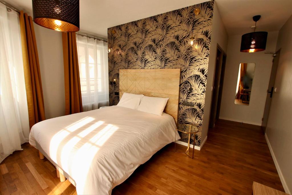 ein Schlafzimmer mit einem weißen Bett und einer schwarz-weißen Tapete in der Unterkunft OXXOTEL in Valognes