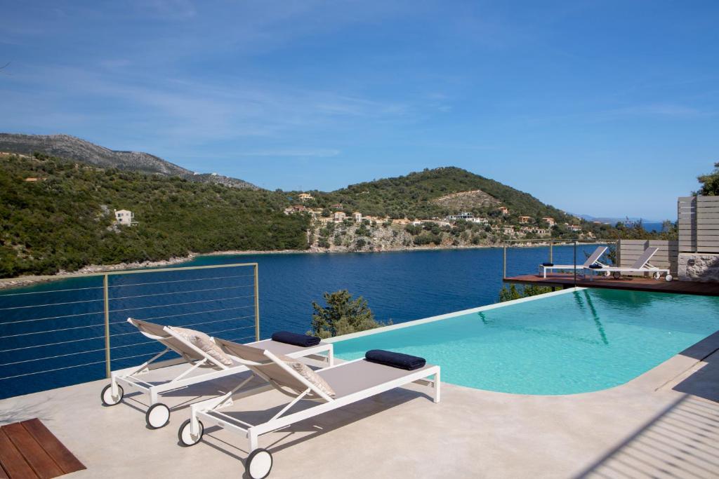 una piscina con 2 tumbonas y vistas al agua en Villa Anthelia-Idyllic view and private access to the sea, en Sivota
