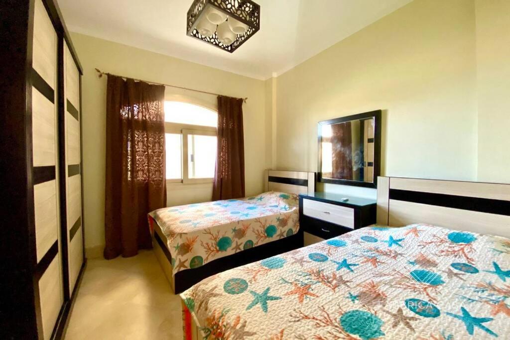1 dormitorio con 2 camas y espejo y 1 cama sidx sidx sidx sidx en Comfy apt by Sentido Marsa Alam, en Marsa Alam