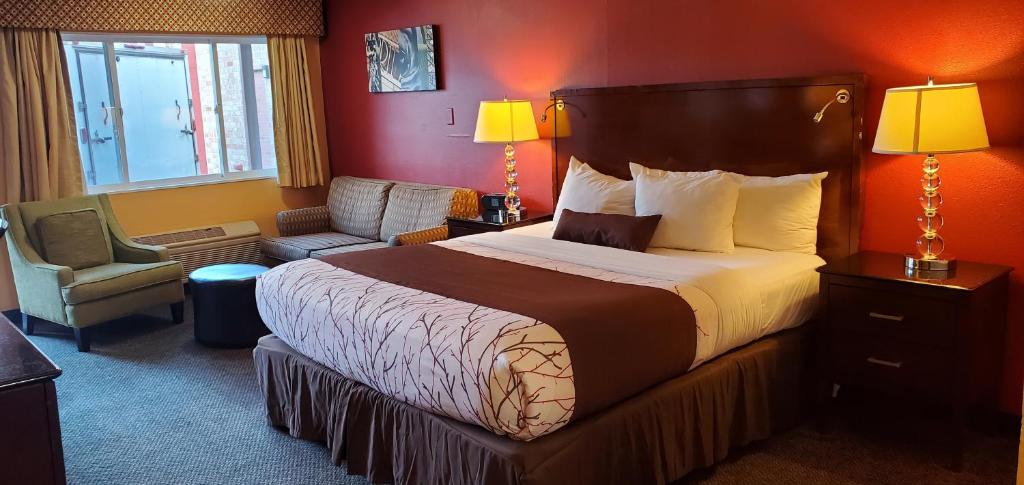 a hotel room with a large bed and a chair at Olympic Inn & Suites in Aberdeen