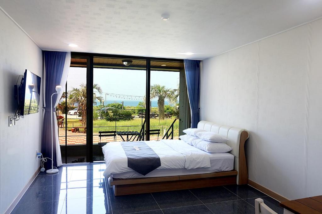 ein Schlafzimmer mit einem Bett und einem großen Fenster in der Unterkunft J Raum Resort in Seogwipo