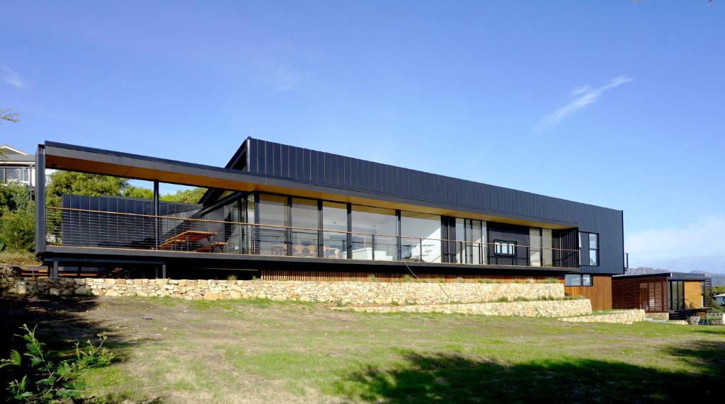 a house with a black roof on top of a field at Atelier in Coles Bay