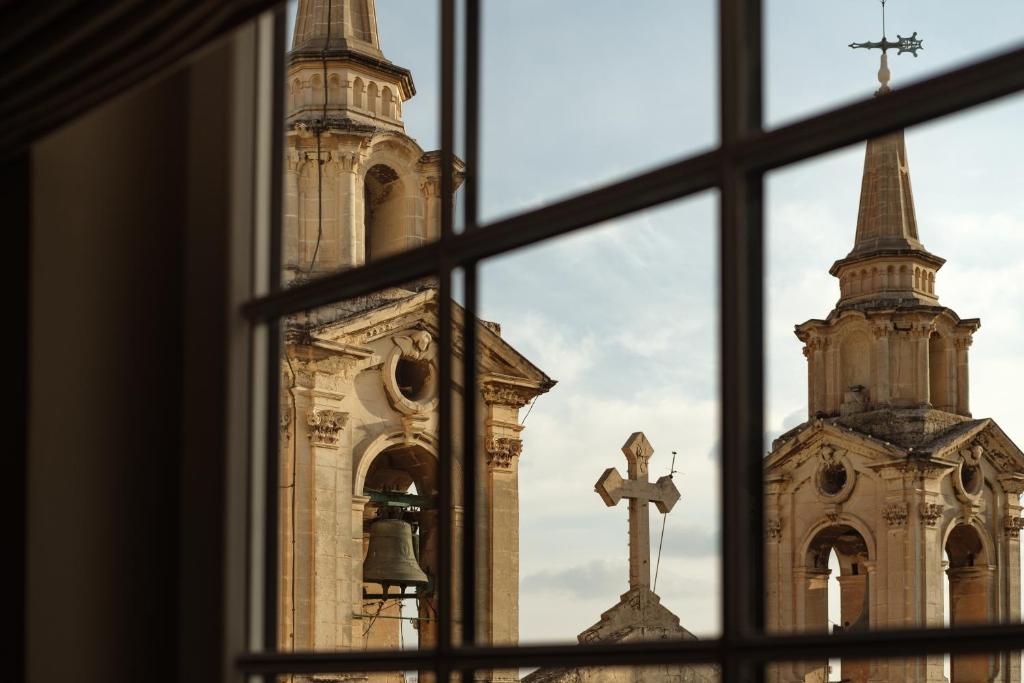 a window view of a church and a cross at 1926 Le Parisot Boutique Suites in Valletta