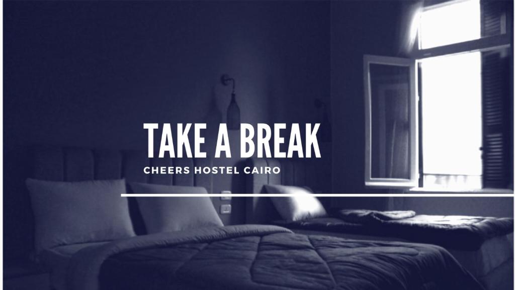 a bedroom with two beds and a window with the words take a break at Cheers Hostel in Cairo