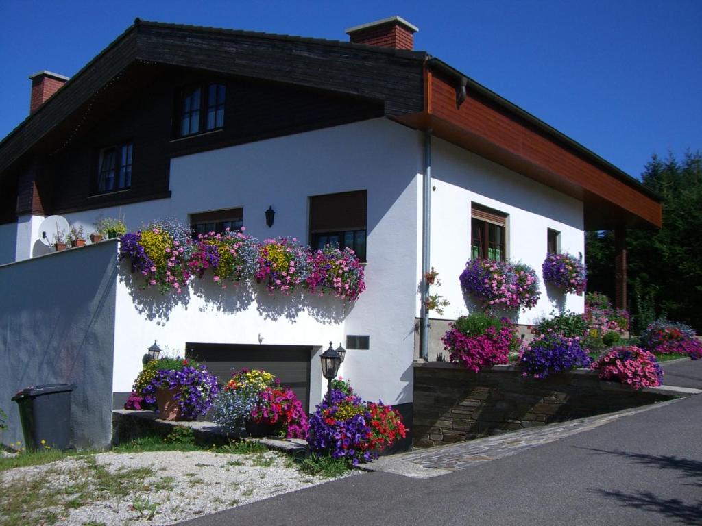 Un edificio blanco con muchas flores. en Haus Wutzl, en Mariazell