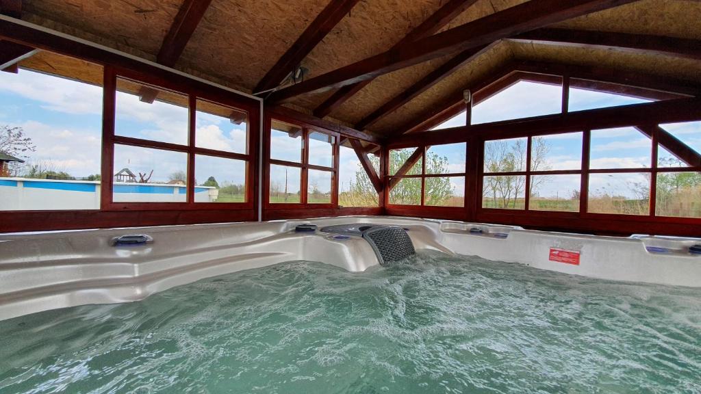 eine große Whirlpool-Badewanne in einem Zimmer mit Fenstern in der Unterkunft Etno Salaš - Etno Ranch - Seosko Turističko Domaćinstvo in Palić