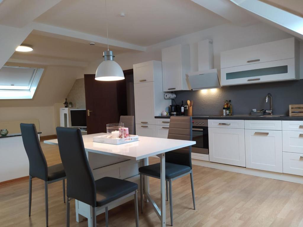 a kitchen with a white table and black chairs at City FeWo in Schwelm