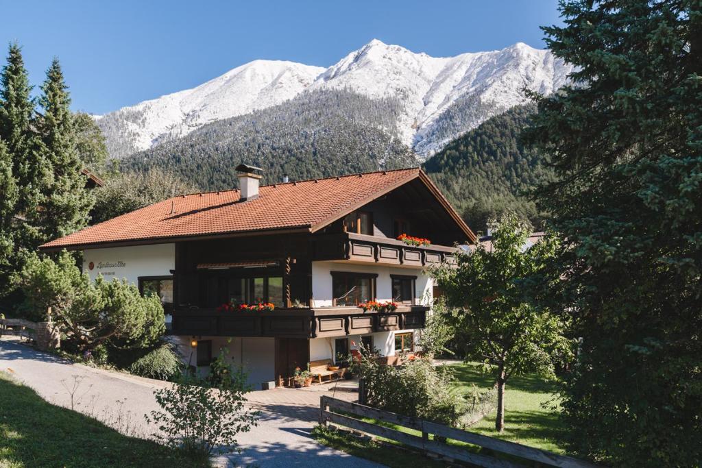 ein Haus mit schneebedeckten Bergen im Hintergrund in der Unterkunft Landhaus Elke in Reith bei Seefeld