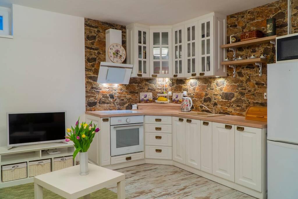 una cucina con armadietti bianchi e una TV di PROVENSÁLSKY RODINNÝ APARTMÁN MANDOLINA a Bojnice