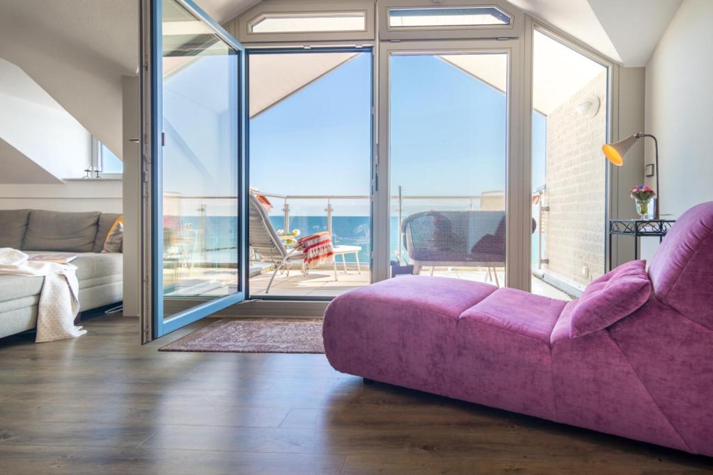 a living room with a purple couch and a balcony at Turm-Appartement Strandburg in Fehmarn