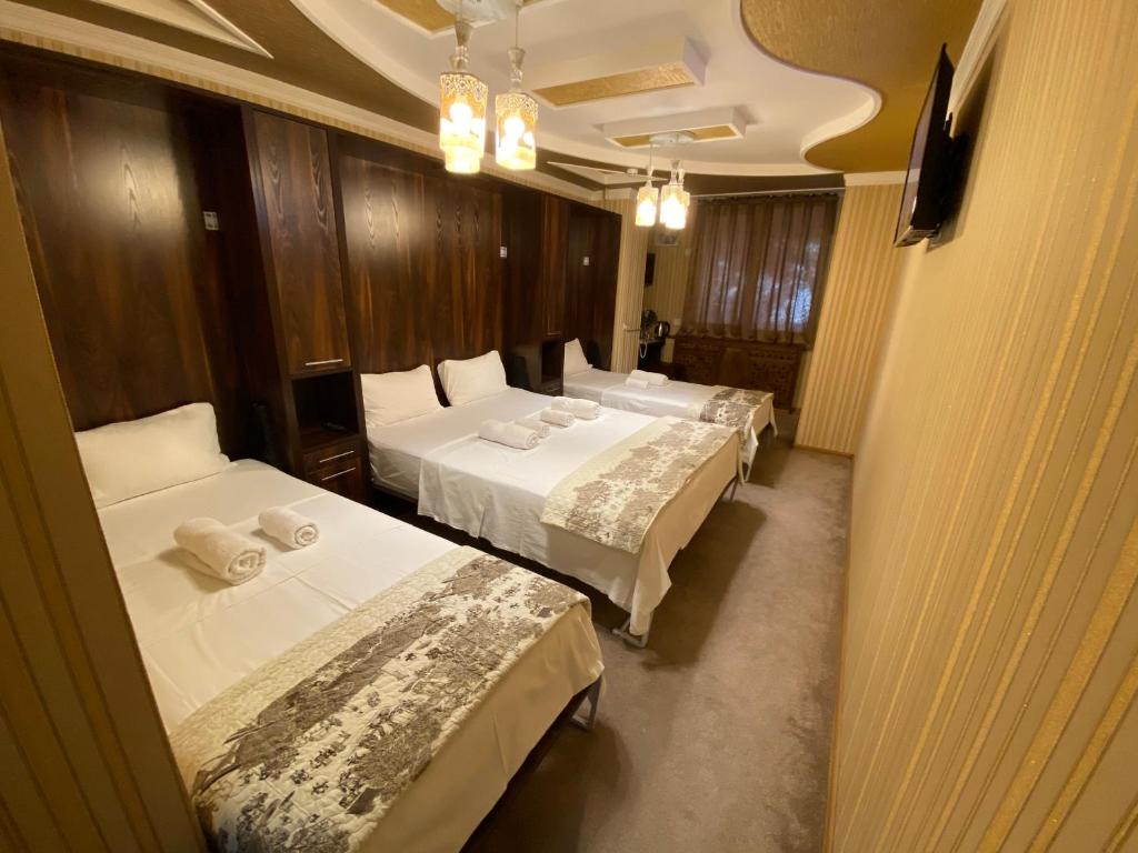 um quarto de hotel com três camas com lençóis brancos em BUDGET HOSTEL em Tashkent