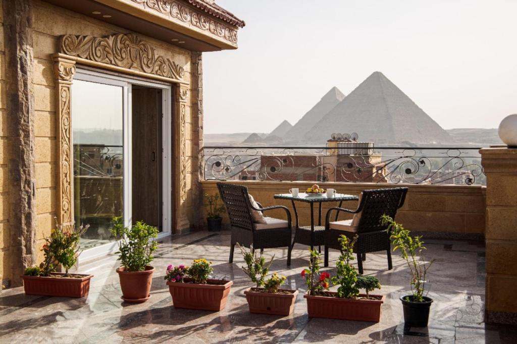 開羅的住宿－Gardenia Inn，阳台配有桌椅和金字塔。