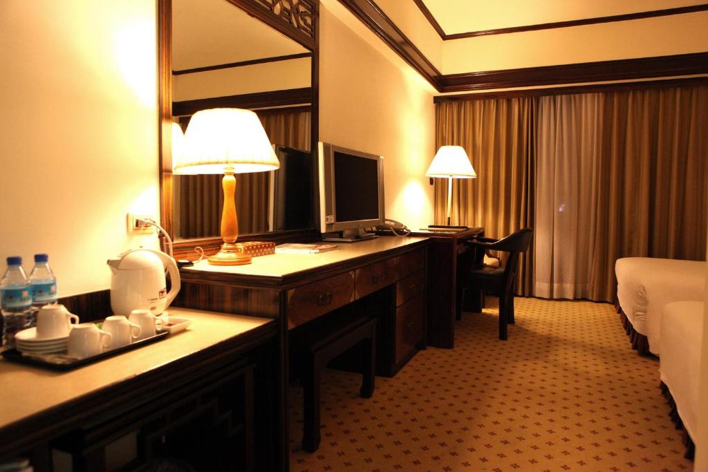 a hotel room with a desk with a bed and a mirror at King&#39;s Town Hotel in Kaohsiung
