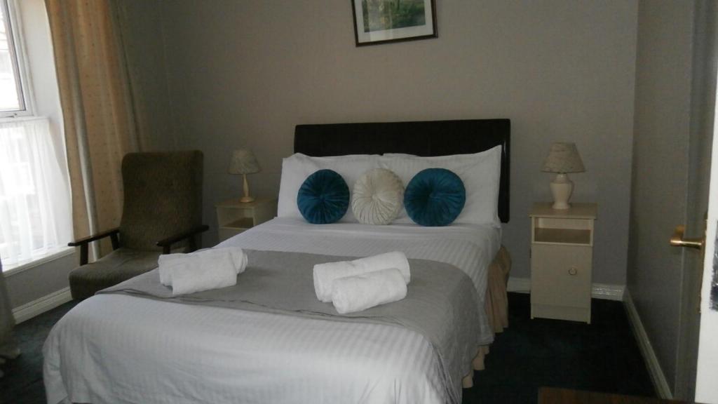 a hotel room with a large bed with blue pillows at Ilenroy House in Skibbereen