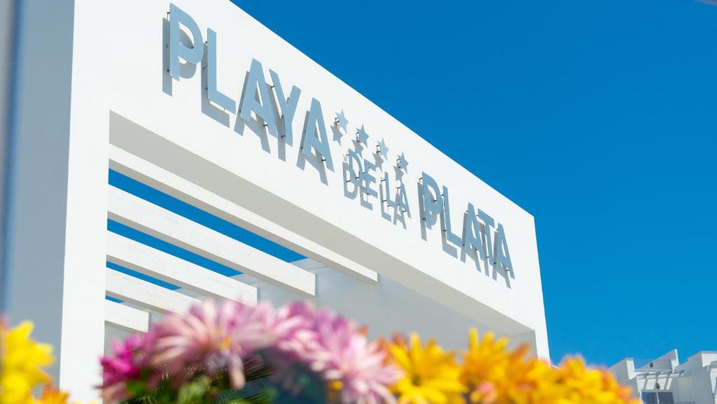um sinal para um banco em frente às flores em Hotel Playa de la Plata em Zahara de los Atunes