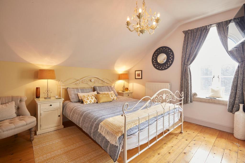 a bedroom with a bed and a chandelier and a window at Chapel Cottage Set in a private courtyard in central location with 2 parking spaces in Kirkby Lonsdale