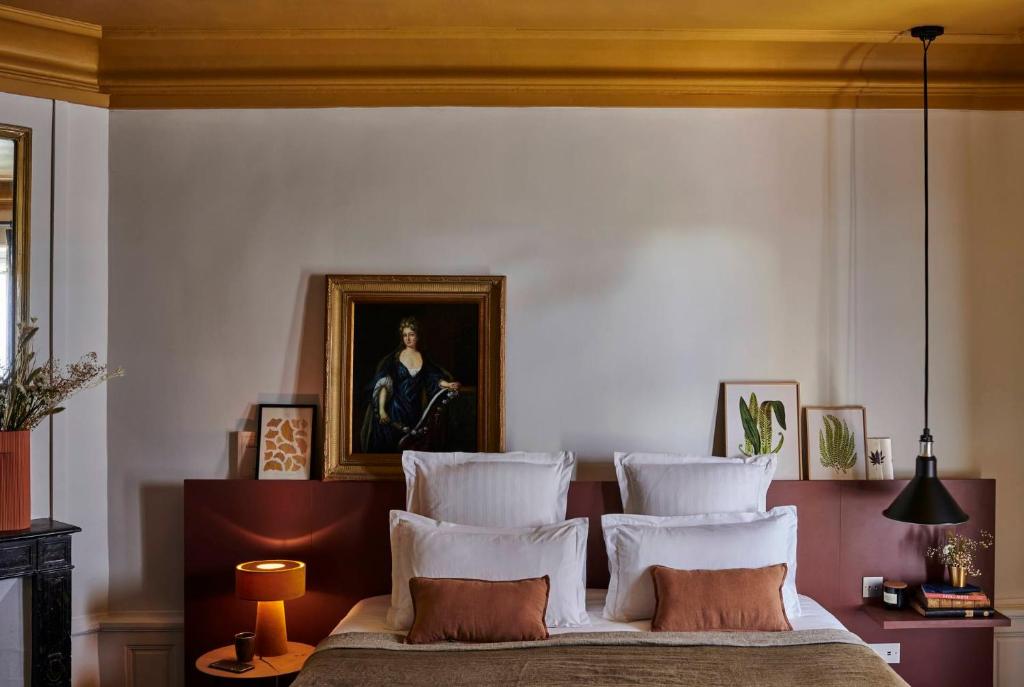 a bedroom with a bed with four pillows on it at Maison du Val - Les Maisons de Campagne in Saint-Germain-en-Laye