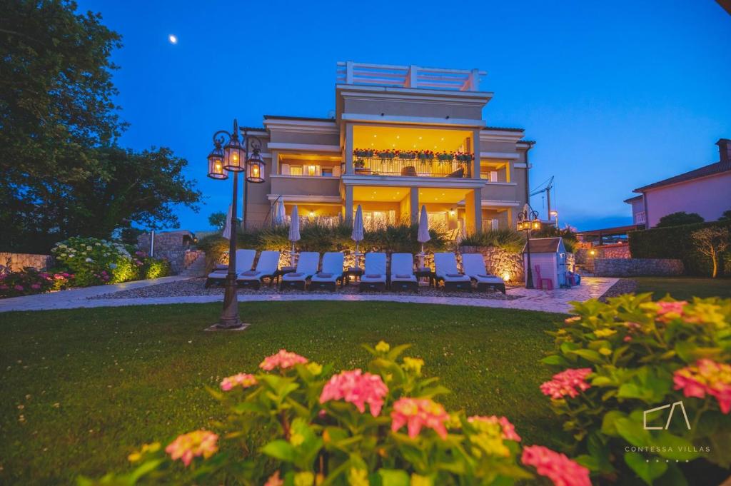 a large house with chairs in front of it at Luxury Apartments Villa Luce in Malinska