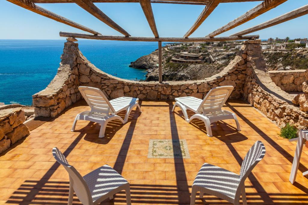 un patio con sedie e l'oceano sullo sfondo di Il Villaggio Del Mago a Lampedusa