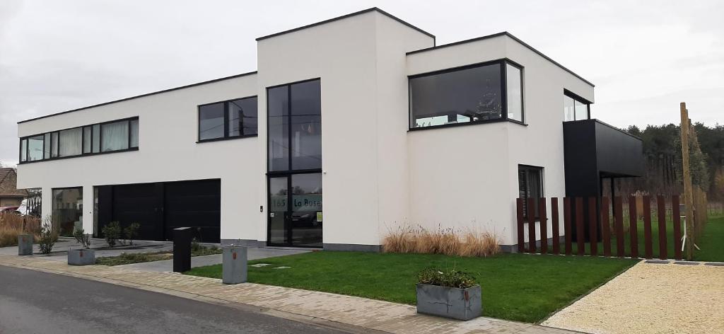 a white building with black windows on a street at La Buse in Koekelare