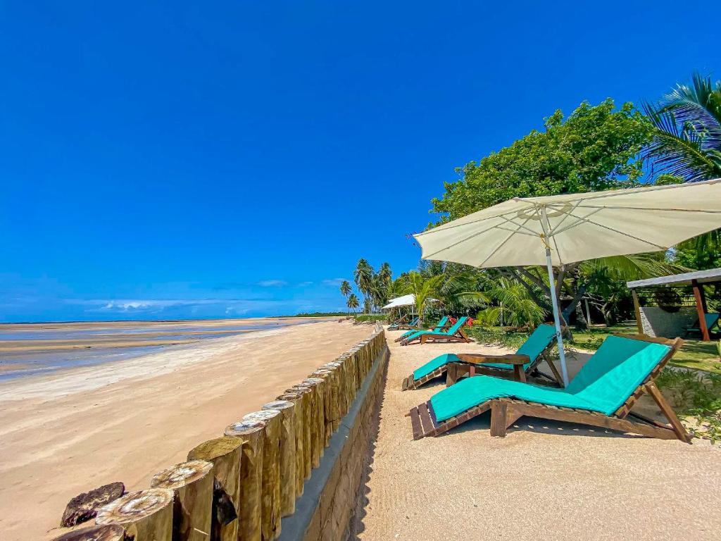 twee stoelen en een parasol op het strand bij Pousada Villa Tatuamunha in Pôrto de Pedras