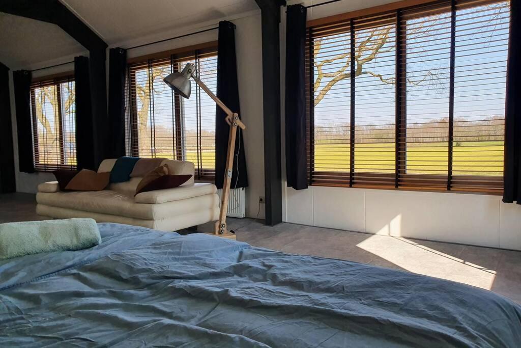 1 dormitorio con cama, sofá y ventanas en Vrijstaand / landelijk appartement met uitzicht!, en De Wijk