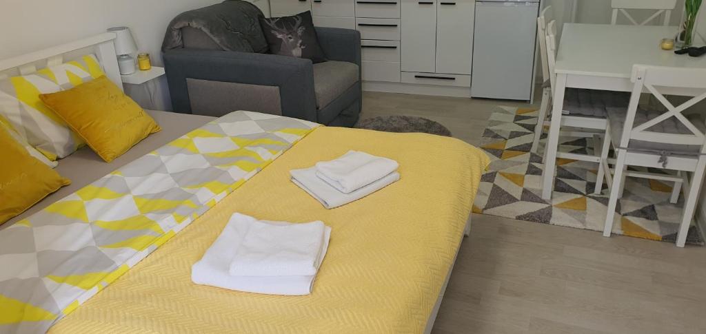 ein Wohnzimmer mit einem gelben Bett und Handtüchern darauf in der Unterkunft Apartman Iva in Nova Varoš