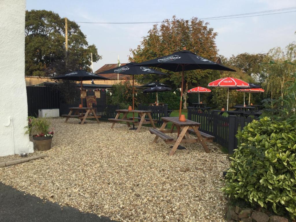 a patio area with umbrellas and chairs at Thelbridge Cross Inn in Crediton