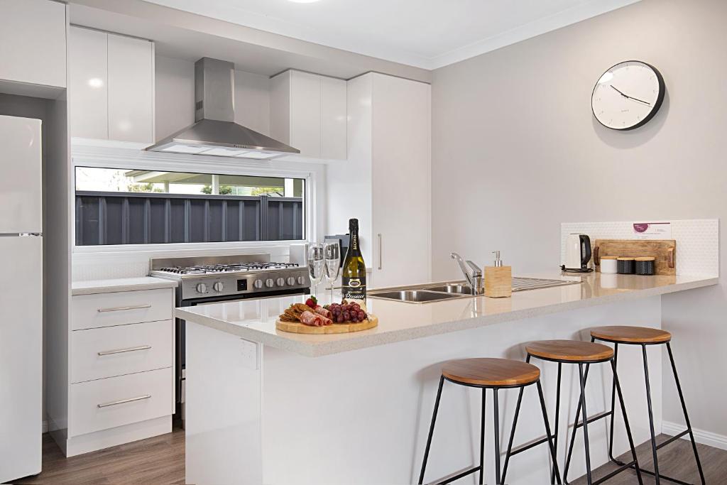 a kitchen with white cabinets and a counter with stools at Milawa Vineyard Views - Guesthouse 1 in Milawa
